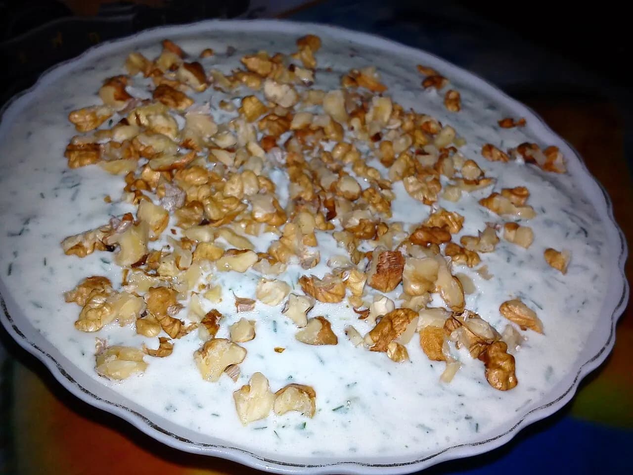 A large bowl of cold tarator soup topped with crushed walnuts